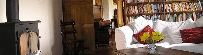 Log burner, books and sofa in the smaller room